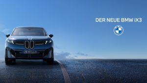 Ein blauer BMW iX3 parkt auf einer Straße unter strahlend blauem Himmel. Der Text DER NEUE BMW iX3 und das BMW Logo erscheinen auf der rechten Seite des Bildes.