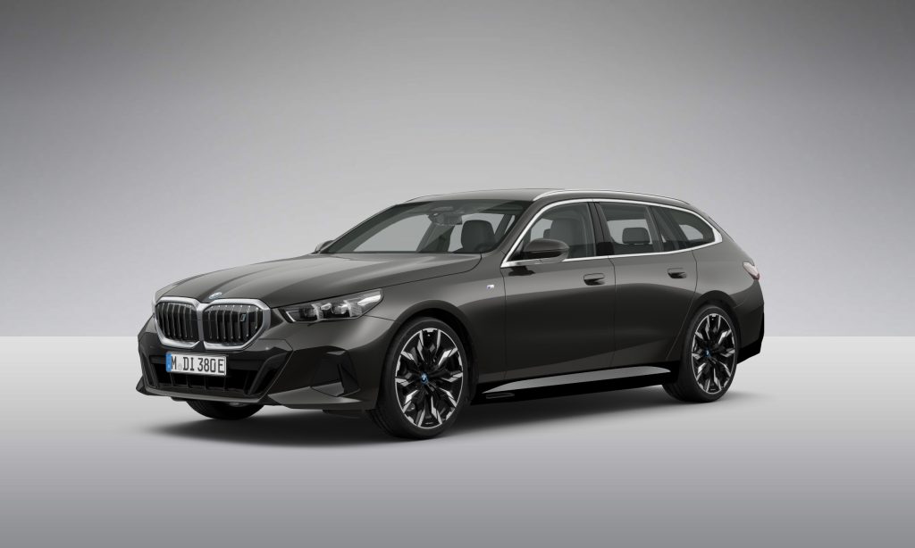 Ein schwarzer BMW 5er Touring ist in einem Studio mit grauem Hintergrund geparkt, von vorne links gesehen.