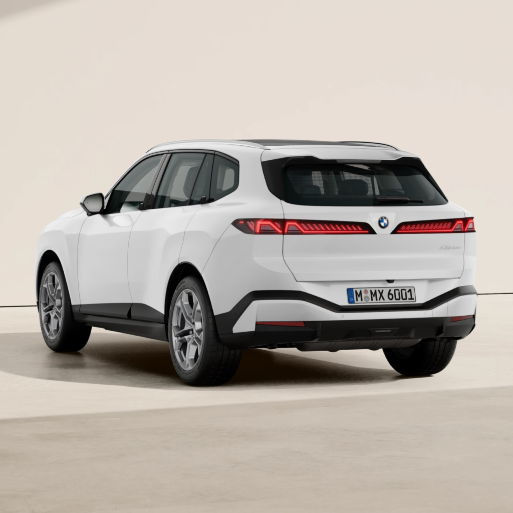 Ein weißer BMW-SUV steht in einem Innenraum auf einem hellen Boden, aufgenommen aus dem hinteren Dreiviertelwinkel. Das Fahrzeug verfügt über schlanke Rückleuchten und ein modernes Design.
