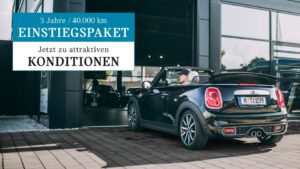 Mini Cooper S Cabrio in der Farbe Schwarz, der Verdeck ist offen. Ein Mann fährt das Auto in das Autohaus rein.