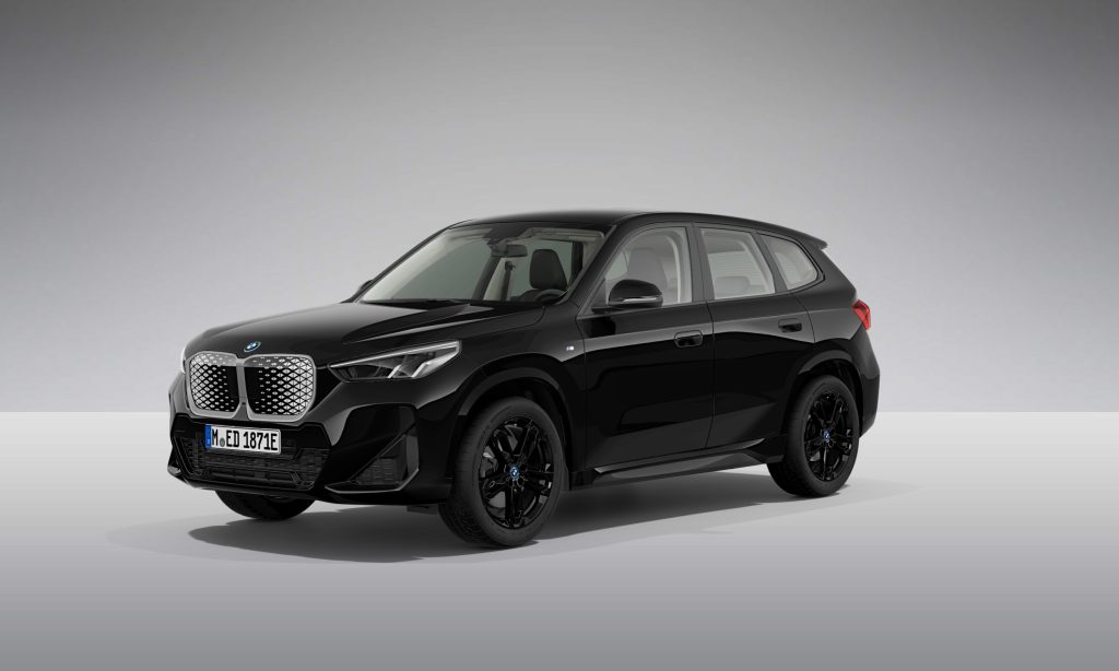Ein schwarzer BMW SUV wird in einer Studioumgebung mit hellgrauem Hintergrund gezeigt. Das Auto hat ein modernes Design mit einem markanten Nierengrill und schlanken Scheinwerfern.