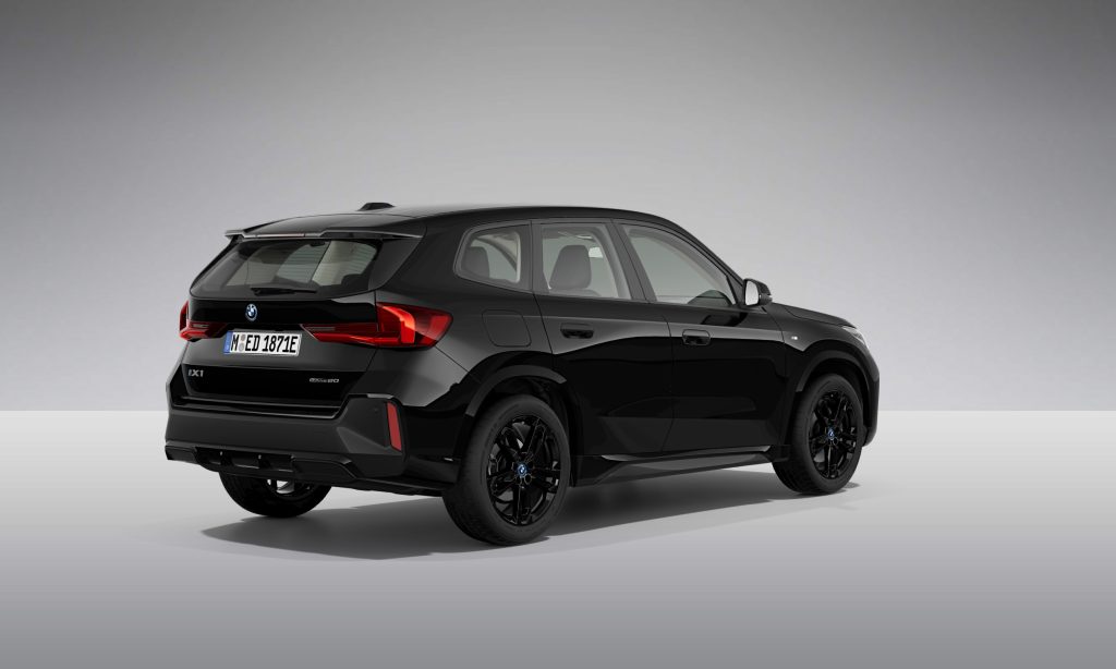 Gezeigt wird ein schwarzer BMW Geländewagen in der hinteren Dreiviertelansicht, der auf einer grauen Fläche mit einfarbig grauem Hintergrund geparkt ist. Das Auto hat schlanke Linien, getönte Scheiben und schwarze Räder.